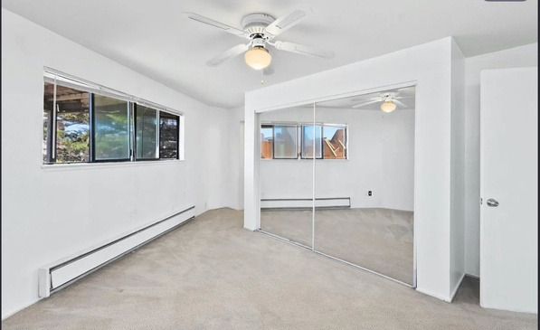 A geodome bedroom before renovation: empty, with a ceiling fan and mirrored closet doors.