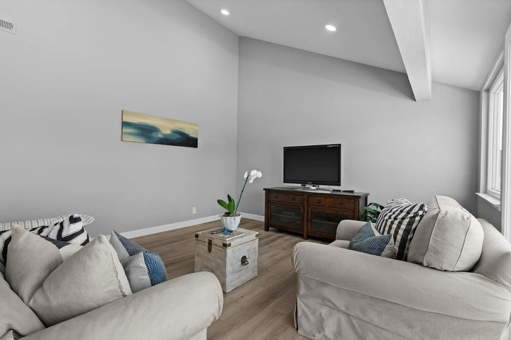 The living room before renovation: two beige sofas and a television on a wooden console.